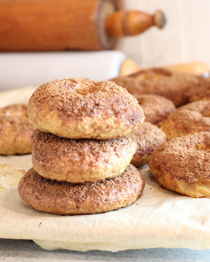 Easy homemade bagels with freshly milled flour setting on parchment paper on kitchen counter beside grain mill and rolling pins